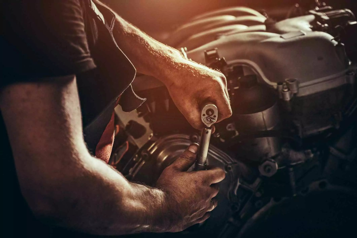 A man is working on a car engine surrounded by clean shop air due to an industrial air cleaner.