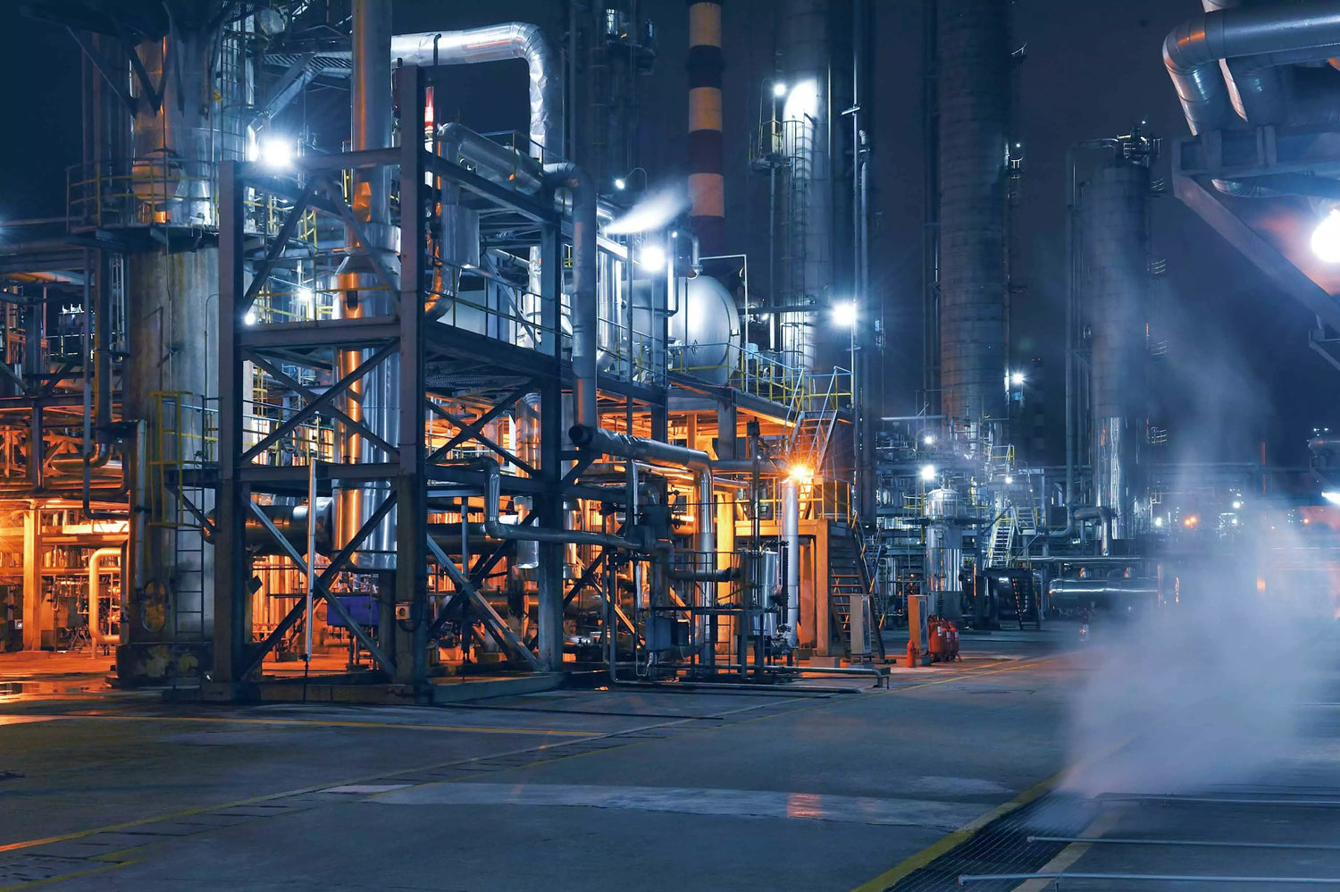 An industrial plant at night with clean air coming out of it.