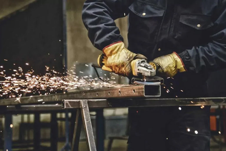 A man operating a grinder in a factory with an industrial air purifier for clean air.