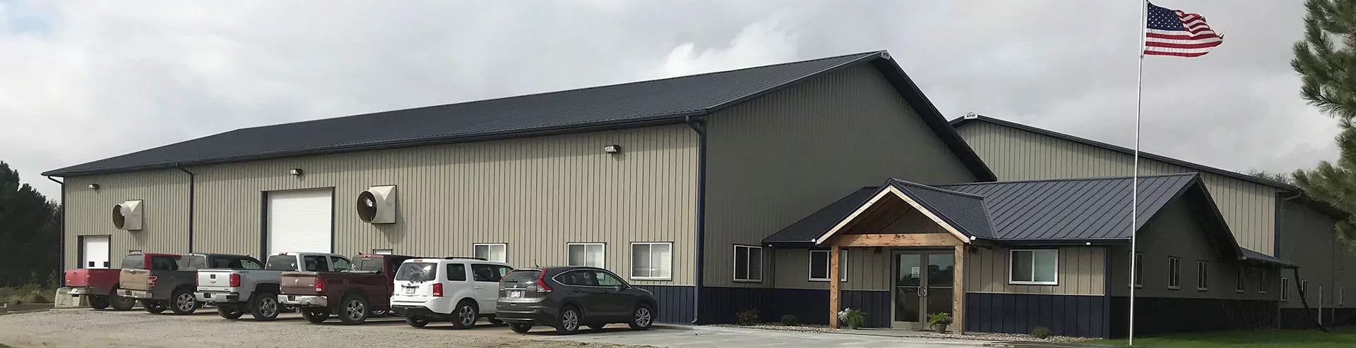 Two clean shop air trucks parked in front of a building with an american flag.