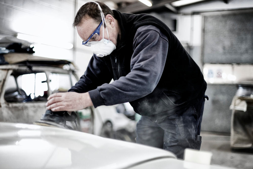 A man using an air cleaner is polishing a car in a clean shop air environment.